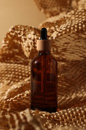 Photo of Glass bottle of cosmetic product on dark beige background