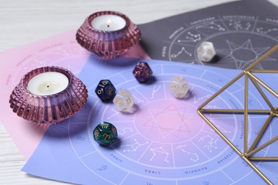 Photo of Zodiac wheels, astrology dices and burning candles on table, closeup
