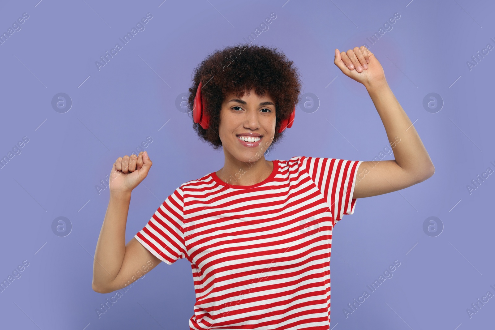 Photo of Happy young woman in headphones enjoying music on purple background