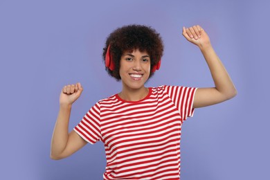 Photo of Happy young woman in headphones enjoying music on purple background