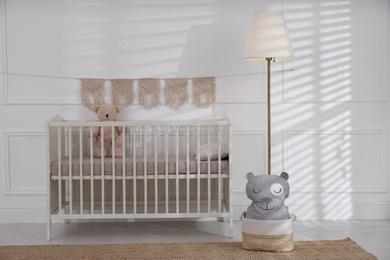 Photo of Cute baby room interior with comfortable crib and teddy bear