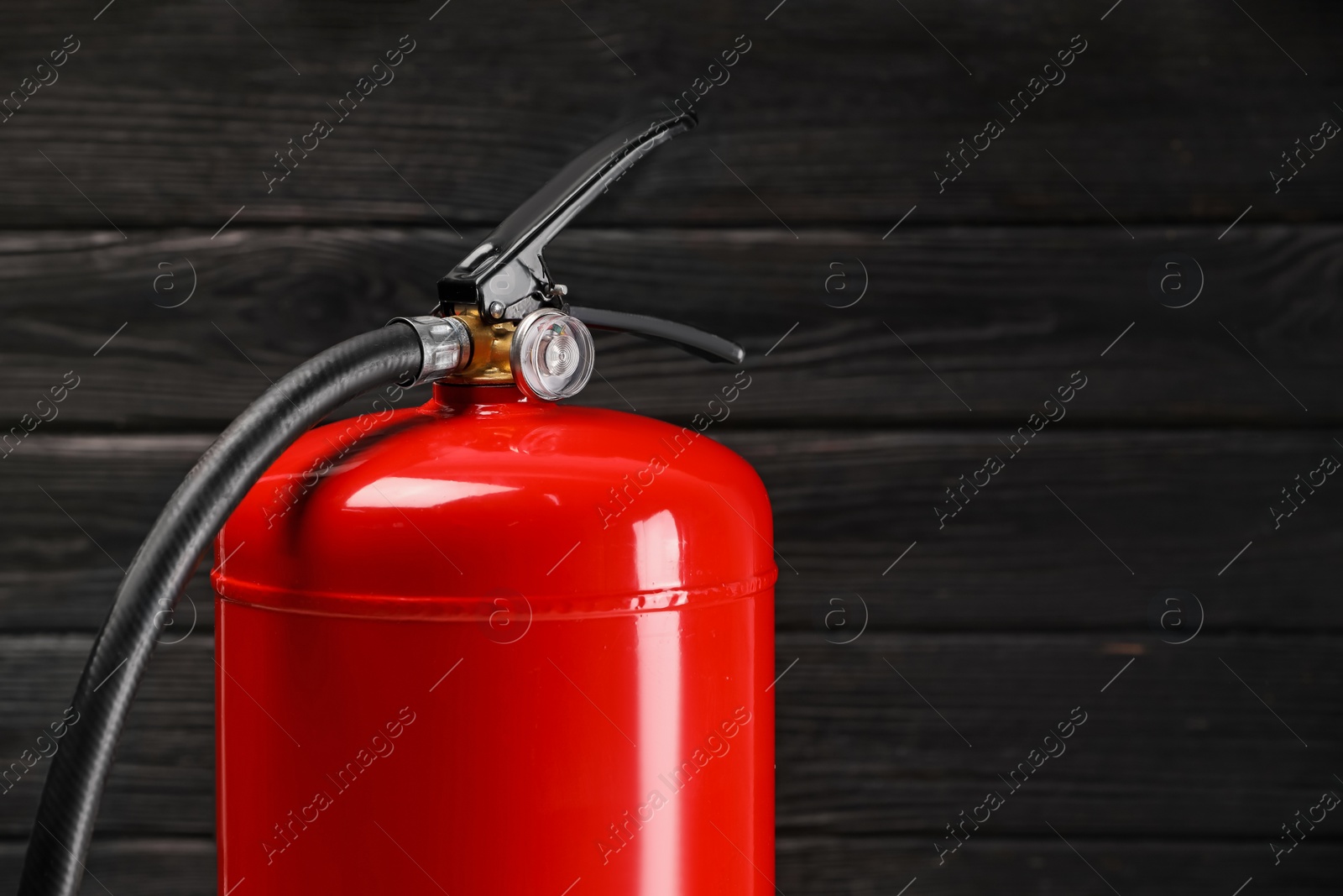 Photo of Fire extinguisher against wooden wall, closeup. Space for text