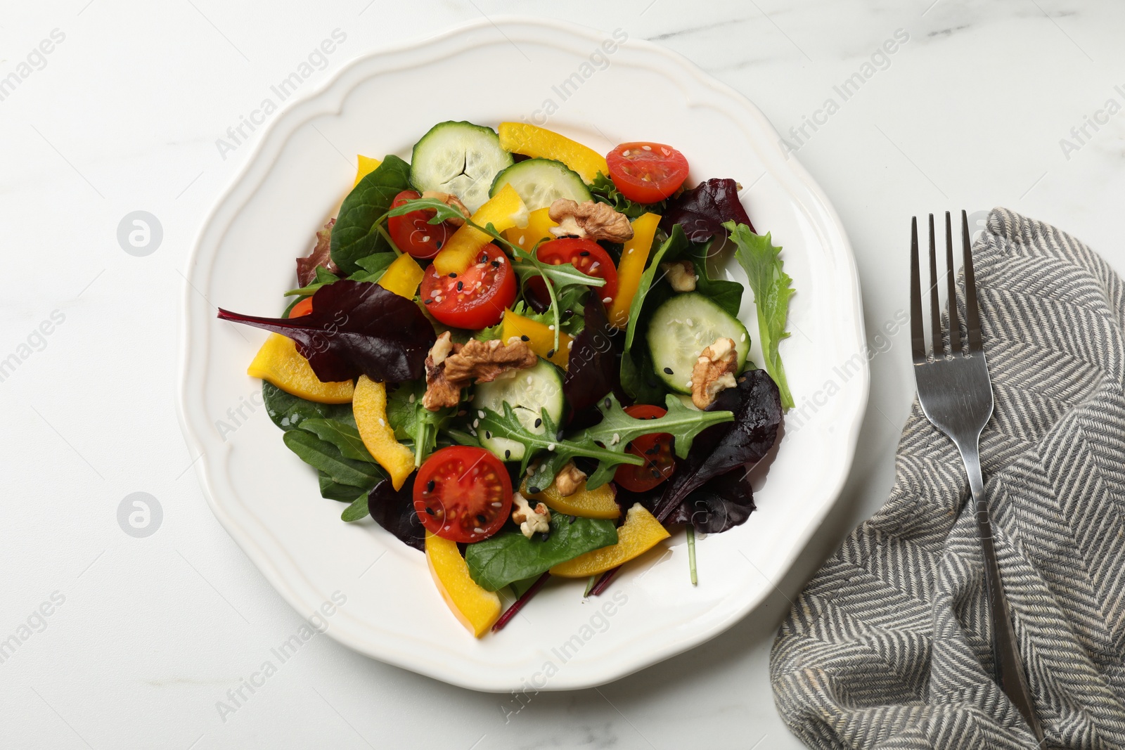 Photo of Tasty fresh vegetarian salad and fork on white marble table, top view