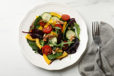 Tasty fresh vegetarian salad and fork on white marble table, top view