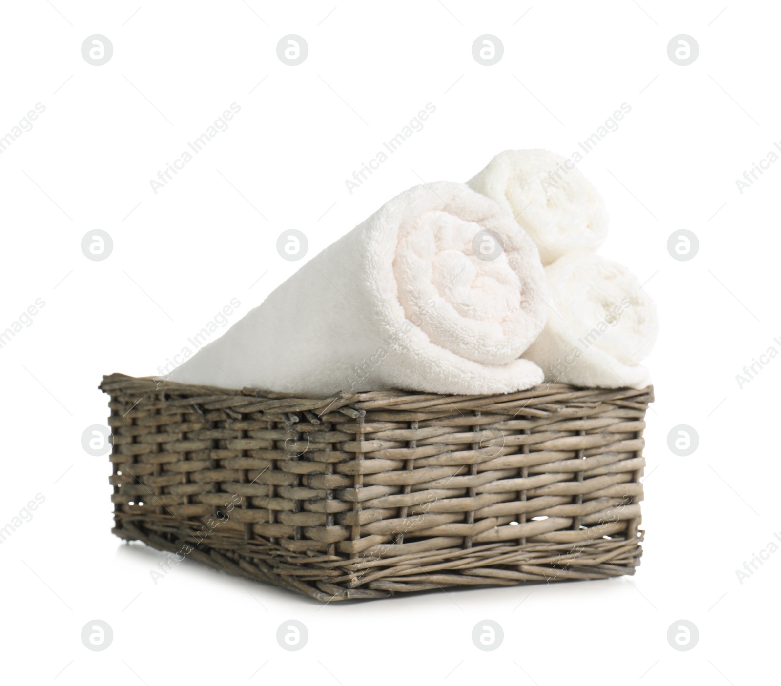 Photo of Rolled soft terry towels in wicker basket on white background