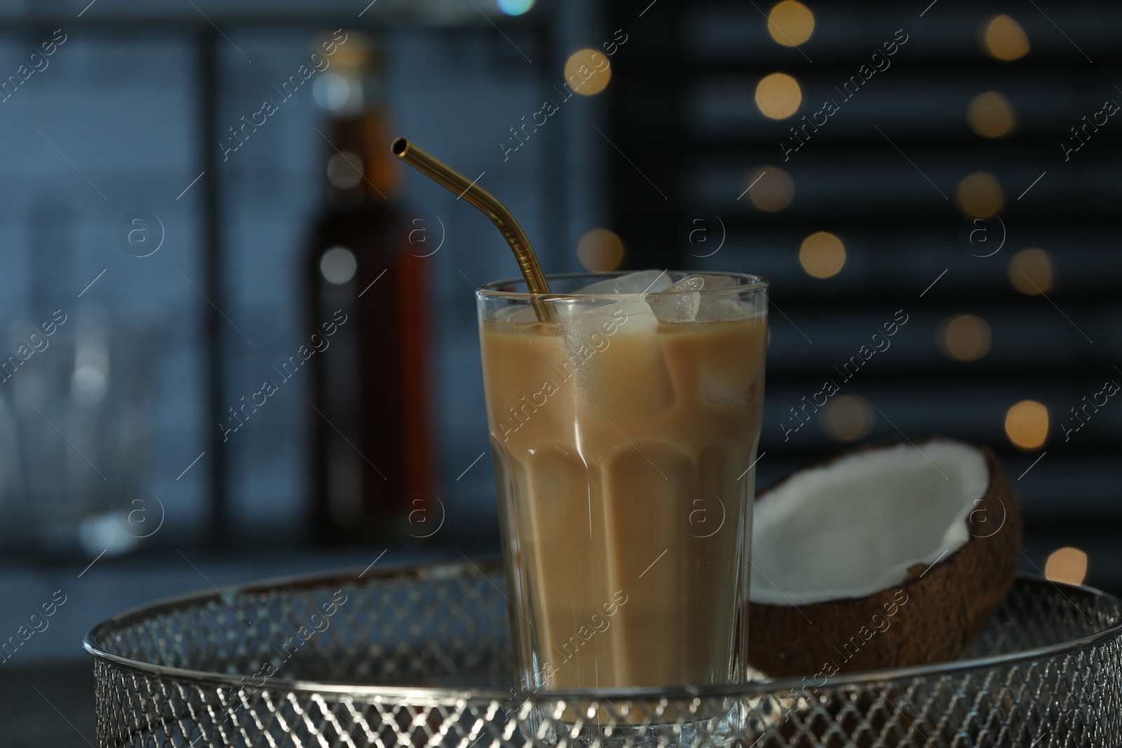 Photo of Glass of iced coffee and coconut on metal tray against blurred lights, closeup
