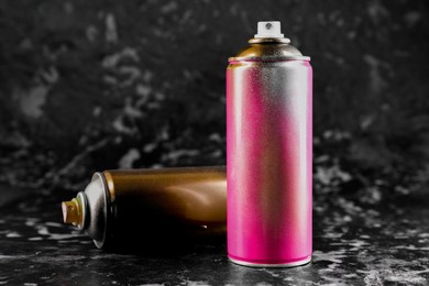 Photo of Used cans of spray paint on black marble background