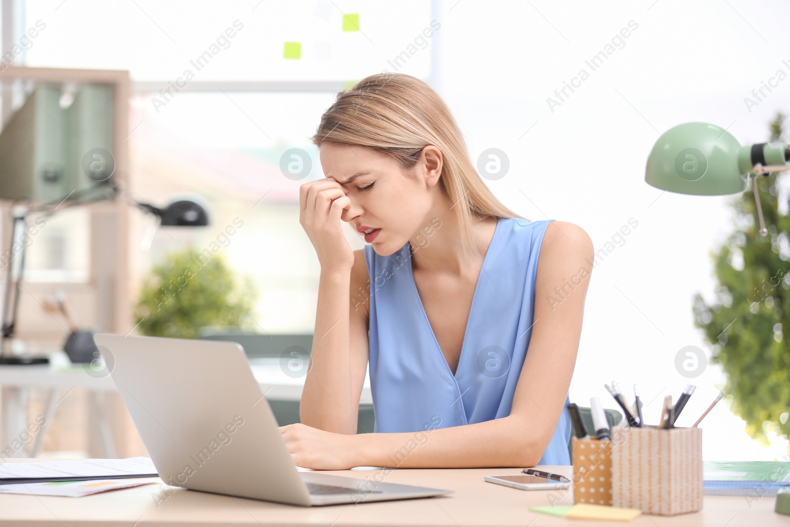 Photo of Young woman suffering from headache in office