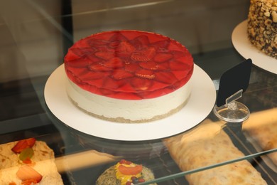 Photo of Delicious cheesecake with strawberries on counter in store
