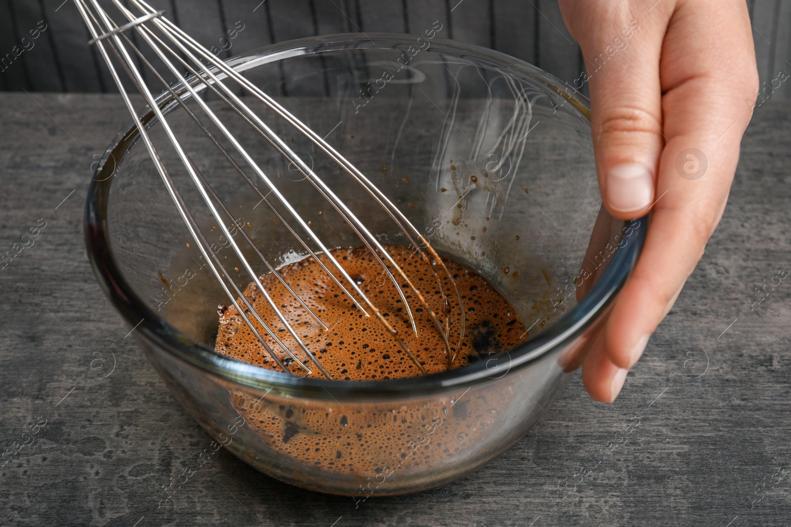 Photo of Woman whipping coffee cream at grey table, closeup