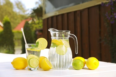 Photo of Water with lemons and limes on white wooden table outdoors