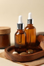 Composition with bottles of cosmetic serum on beige background, closeup
