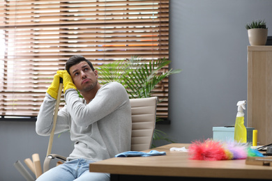 Photo of Lazy man procrastinating while cleaning at home