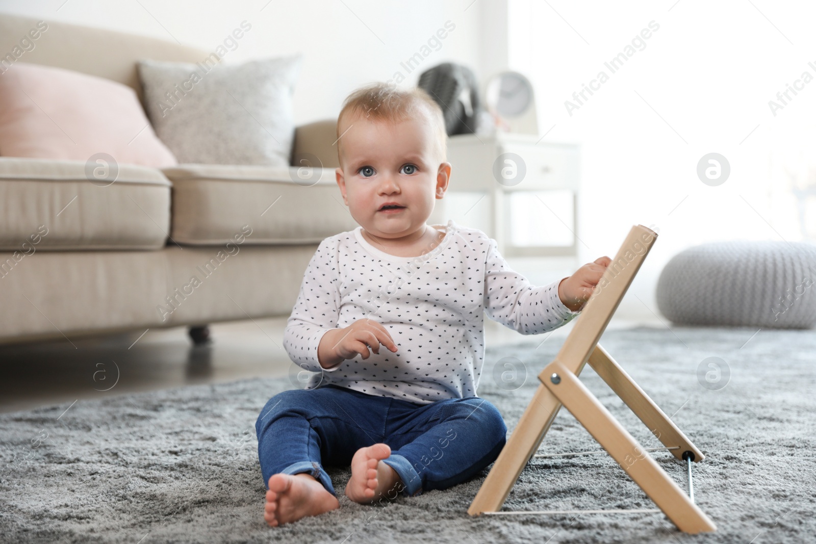 Photo of Cute baby playing with abacus on floor in room