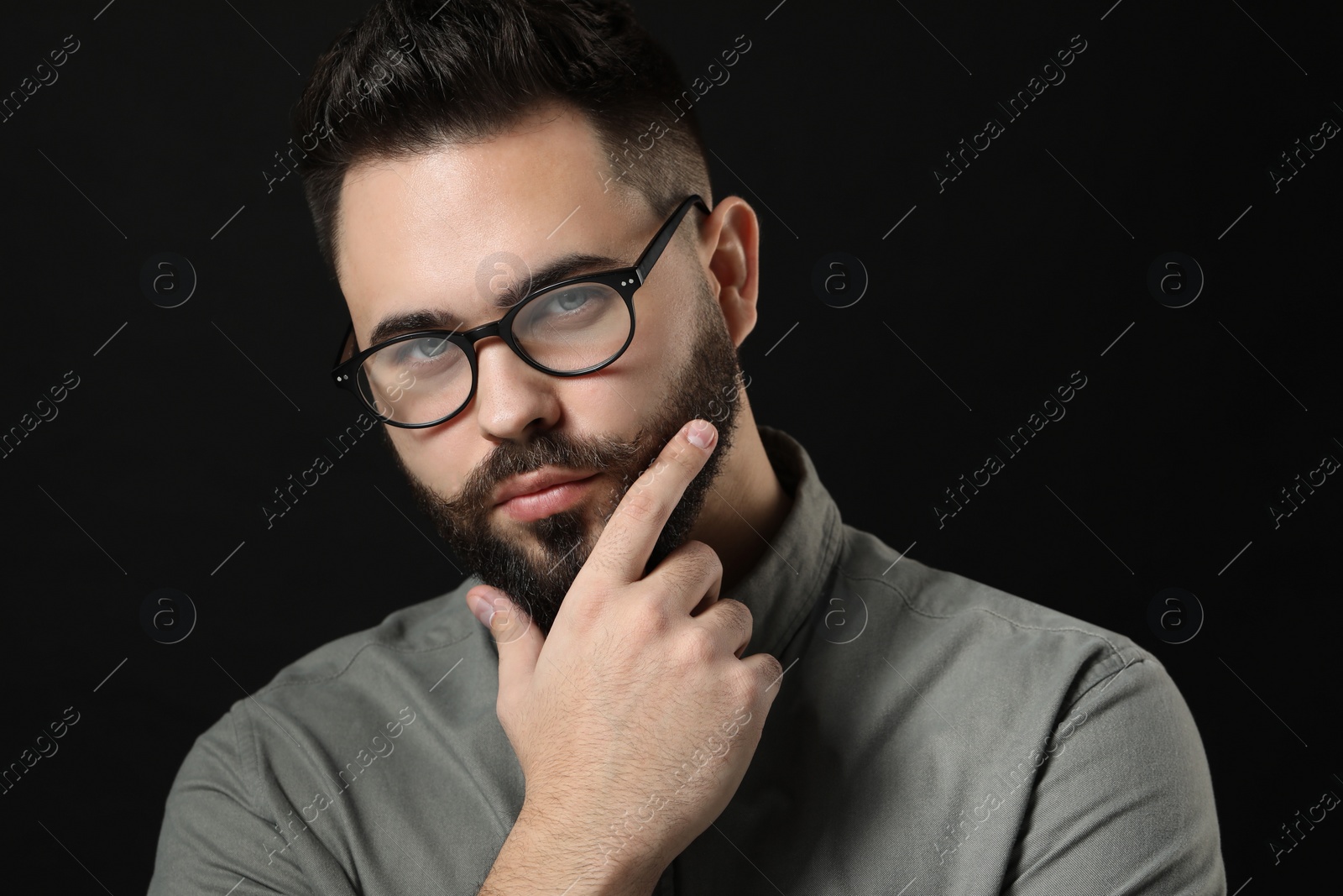 Photo of Young man with mustache touching face on black background