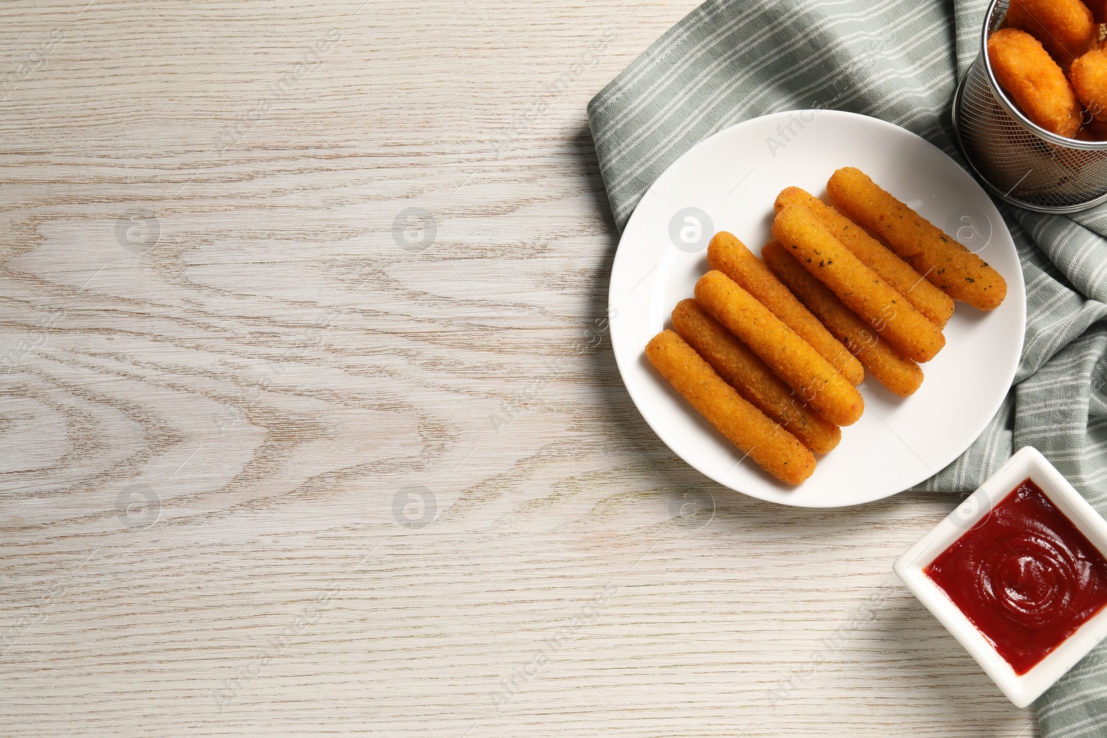 Photo of Tasty ketchup, cheese sticks and chicken nuggets on white wooden table, flat lay. Space for text