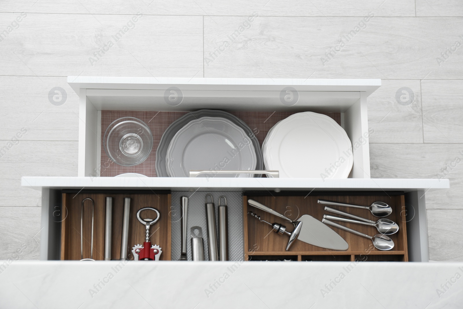 Photo of Open drawers with different dishware and utensils in kitchen, top view