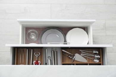 Photo of Open drawers with different dishware and utensils in kitchen, top view