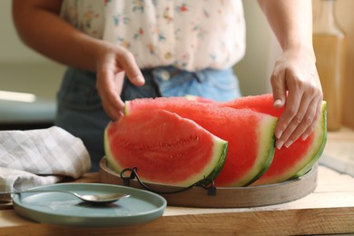 Woman with slices fresh juicy watermelon at wooden table, closeup