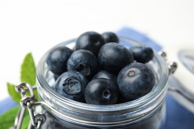 Photo of Glass jar of tasty fresh blueberries on table, closeup