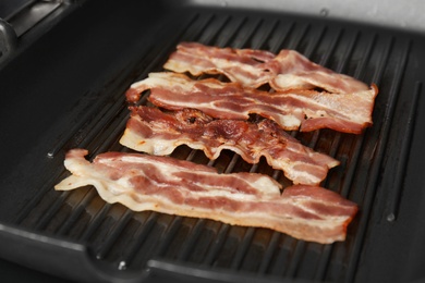 Photo of Slices of tasty fried bacon in grill pan, closeup