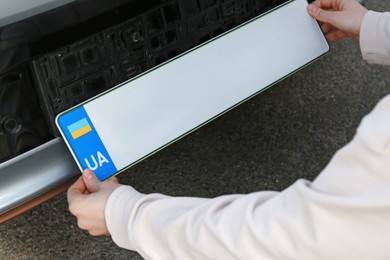 Woman installing vehicle registration plate outdoors, closeup