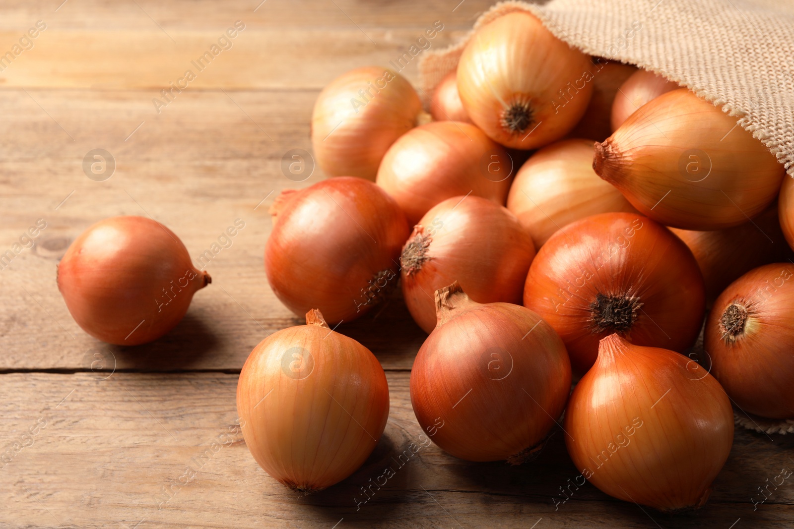 Photo of Many ripe onions on wooden table, closeup