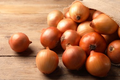 Photo of Many ripe onions on wooden table, closeup
