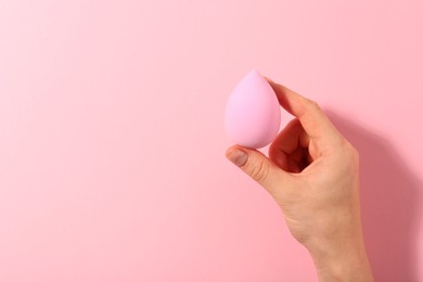 Photo of Woman with makeup sponge on pink background, top view. Space for text