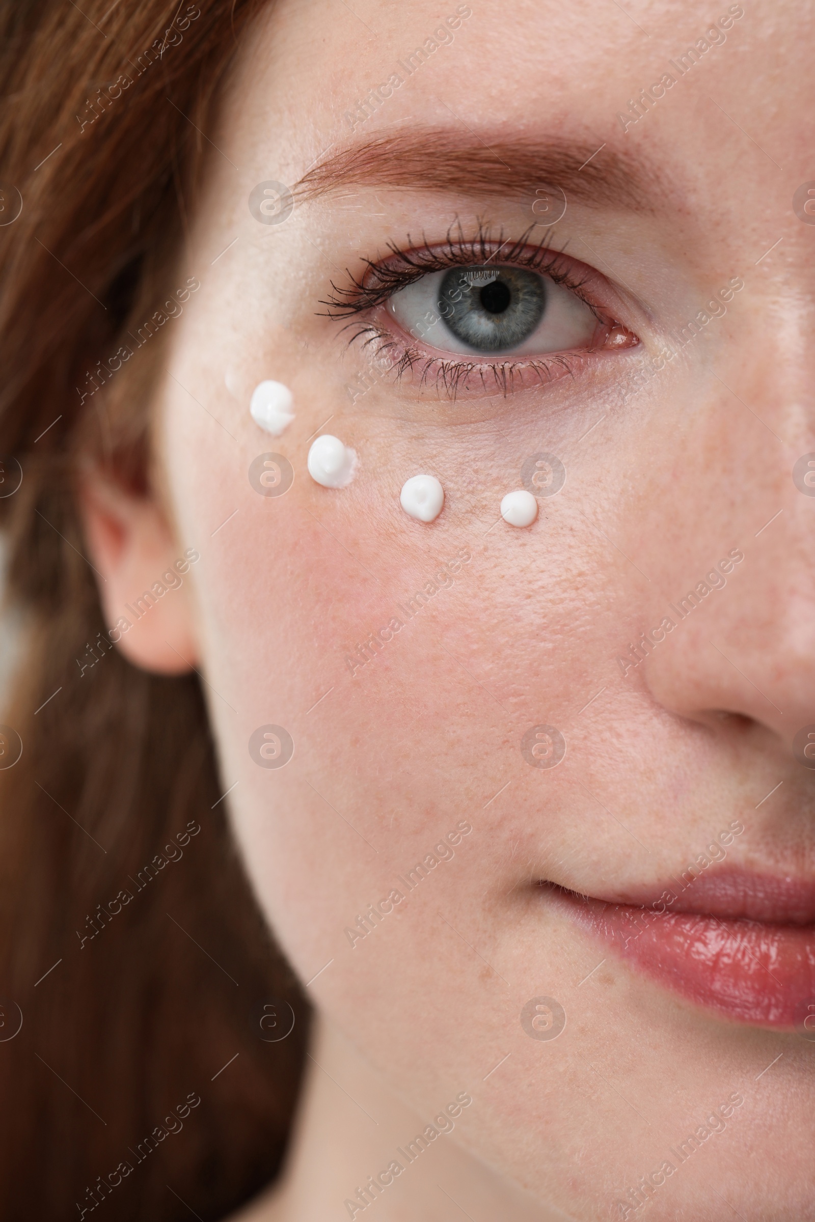 Photo of Beautiful woman with freckles and cream on her face, closeup