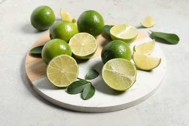 Photo of Fresh ripe limes and leaves on light table