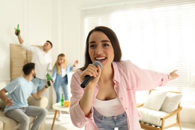Photo of Young woman singing karaoke with friends at home