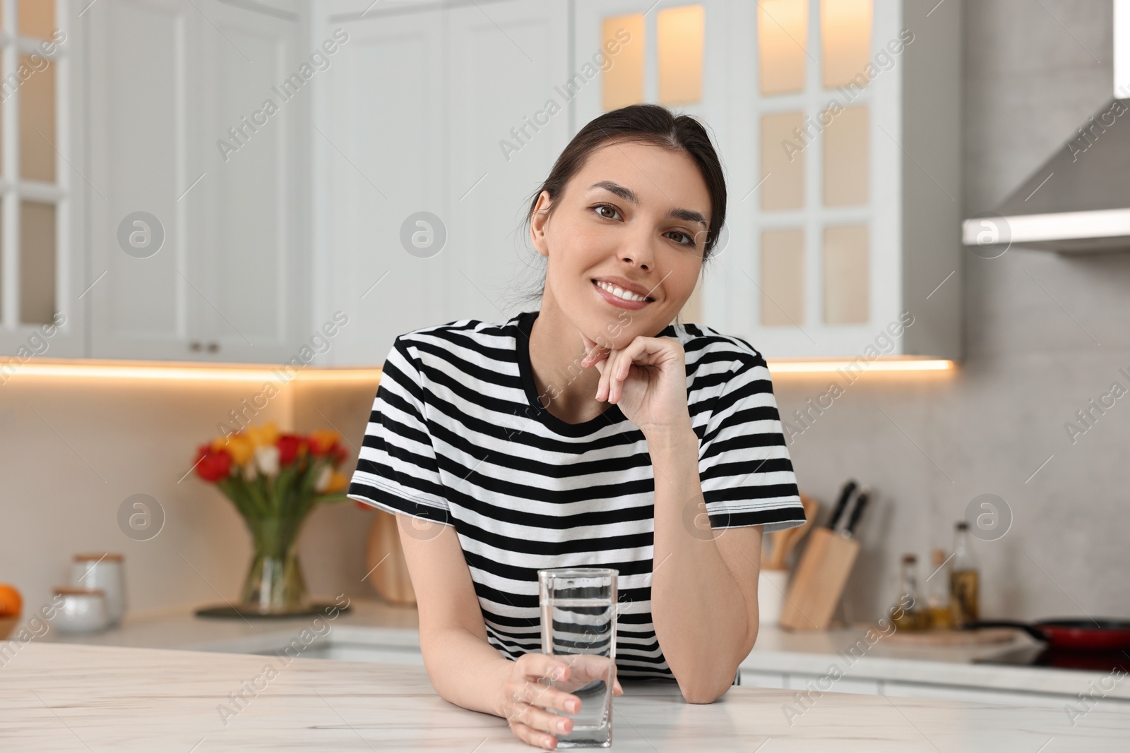 Photo of Woman with glass of water at countertop in kitchen