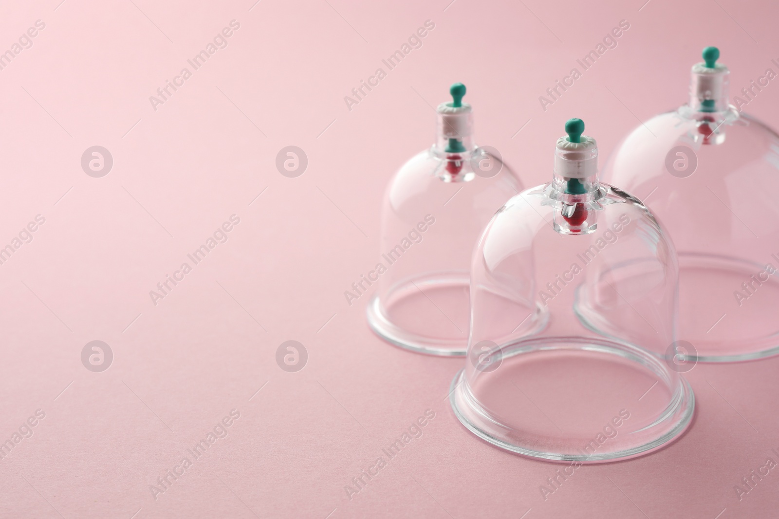 Photo of Plastic cups on pink background, space for text. Cupping therapy