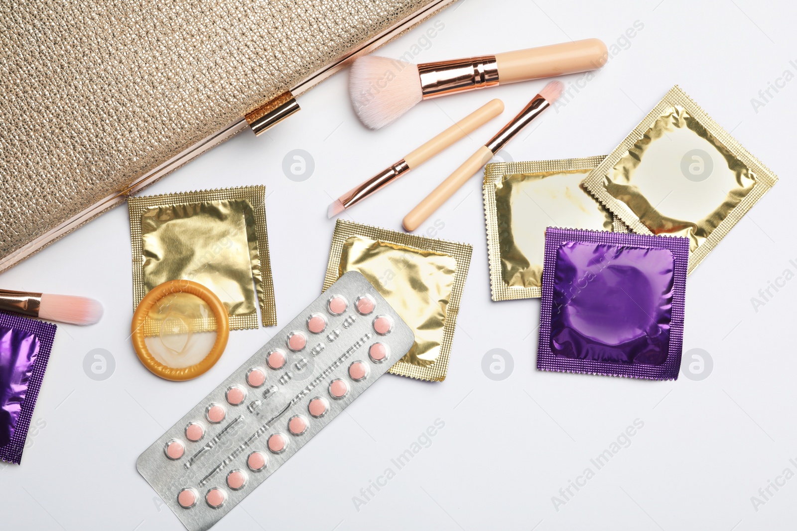 Photo of Flat lay composition with birth control pills and condoms on light background. Safe sex concept