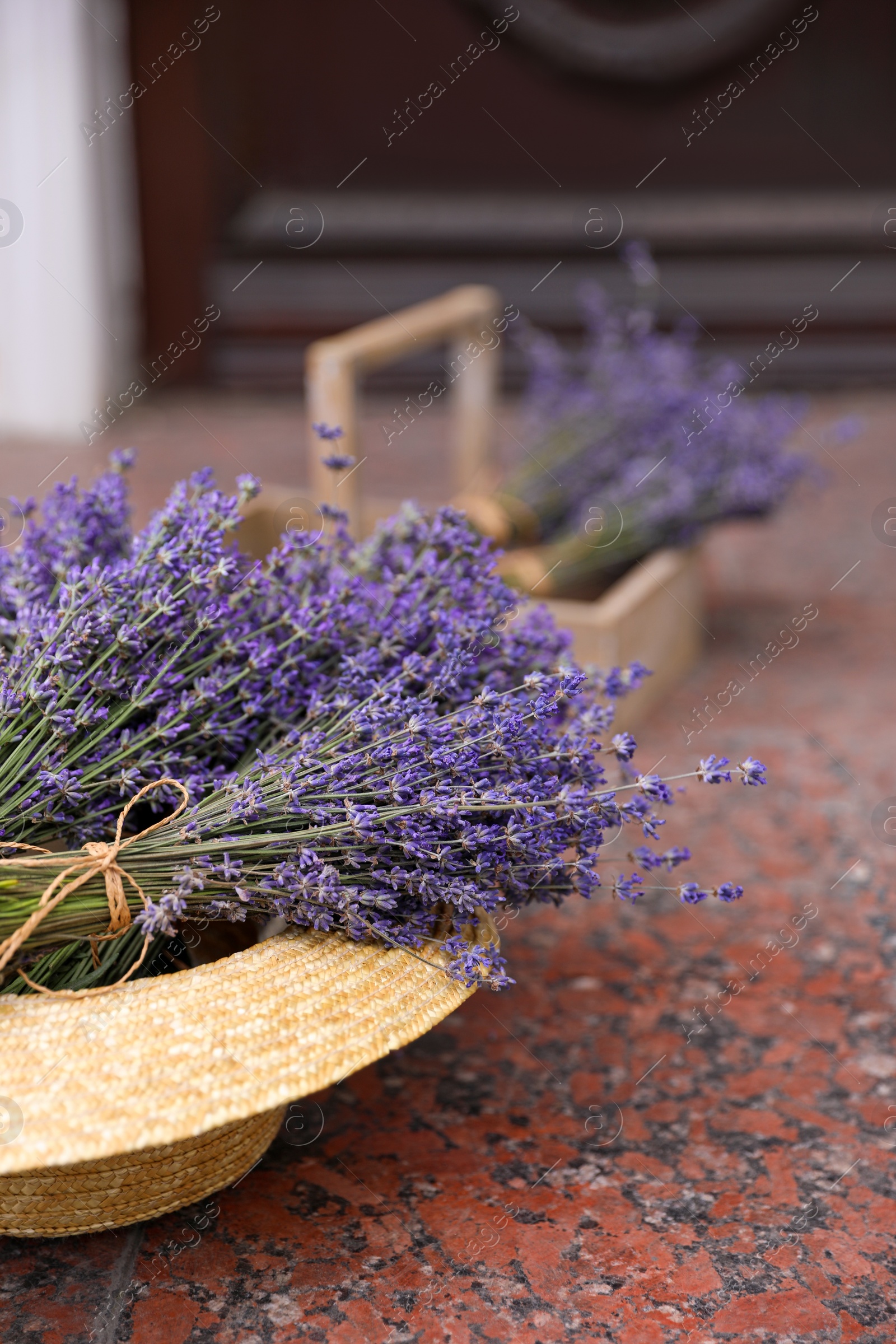 Photo of Beautiful lavender flowers and straw hat on marble tiles outdoors