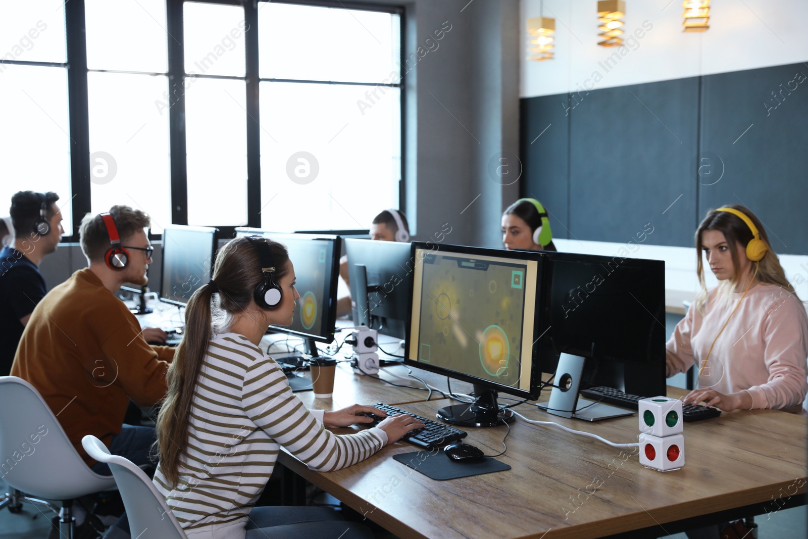 Photo of Group of people playing video games in internet cafe