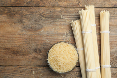 Photo of Rice and raw noodles on wooden table, flat lay. Space for text