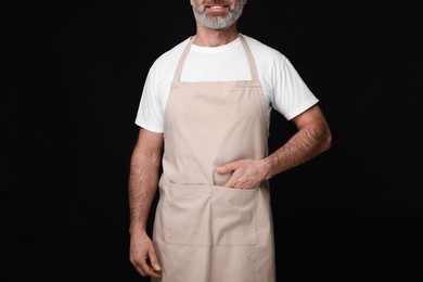 Photo of Man wearing kitchen apron on black background, closeup. Mockup for design