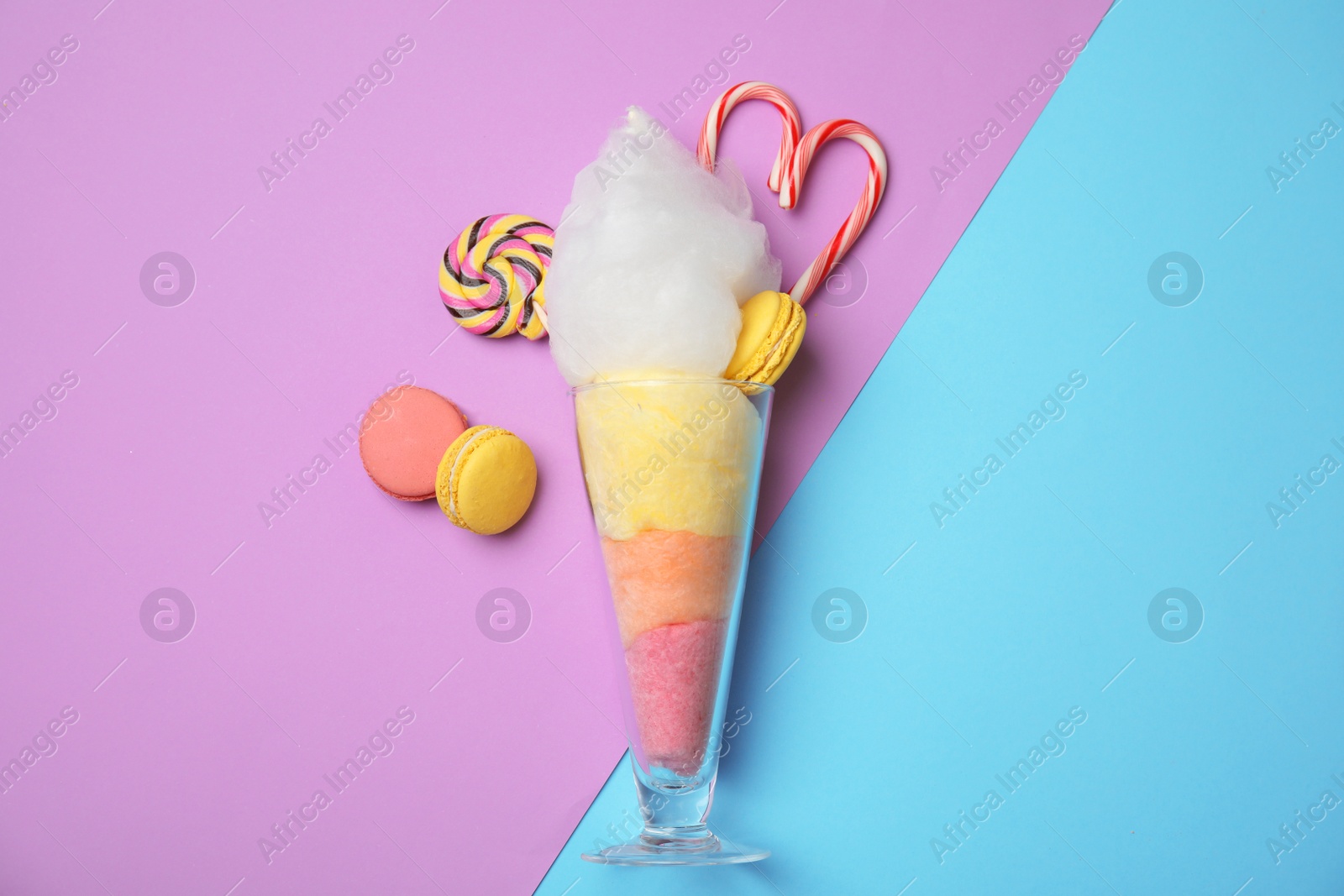 Photo of Composition with cotton candy in glass on color background, top view