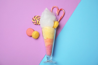 Composition with cotton candy in glass on color background, top view