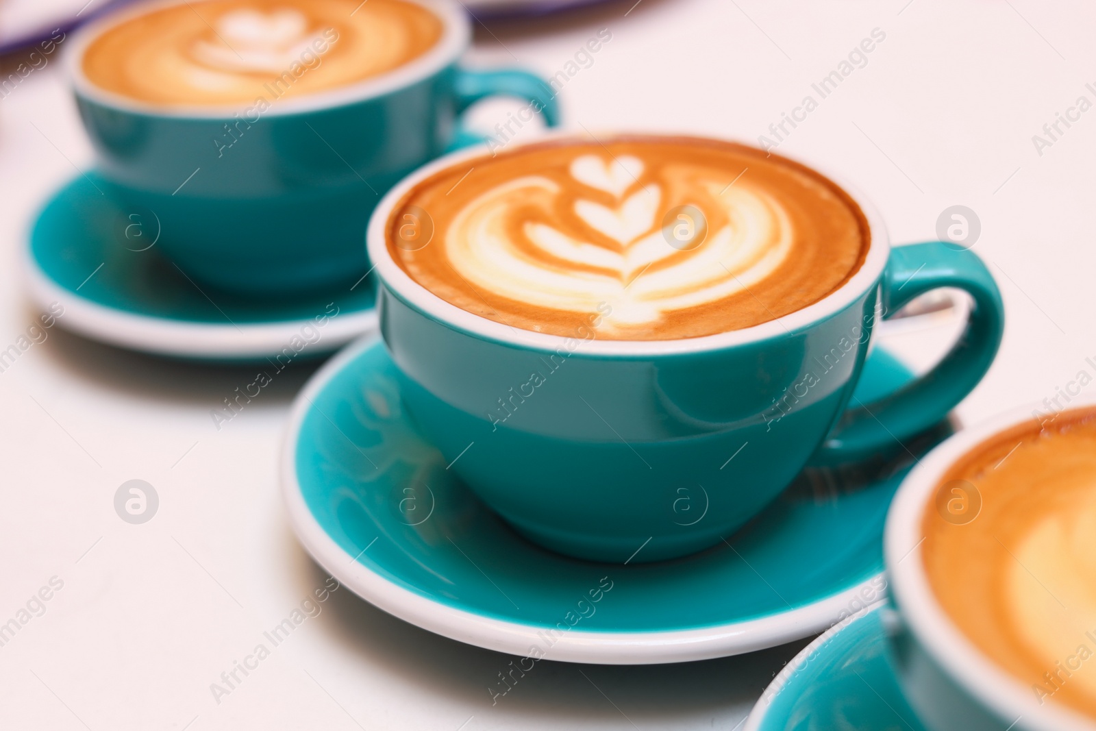 Photo of Cups of aromatic coffee on beige background, closeup