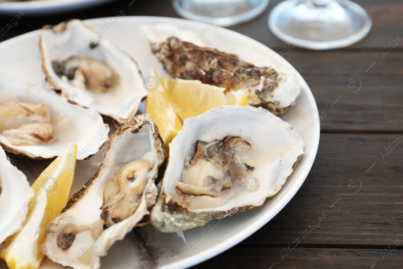 Photo of Fresh oysters and cut juicy lemon served on table, closeup