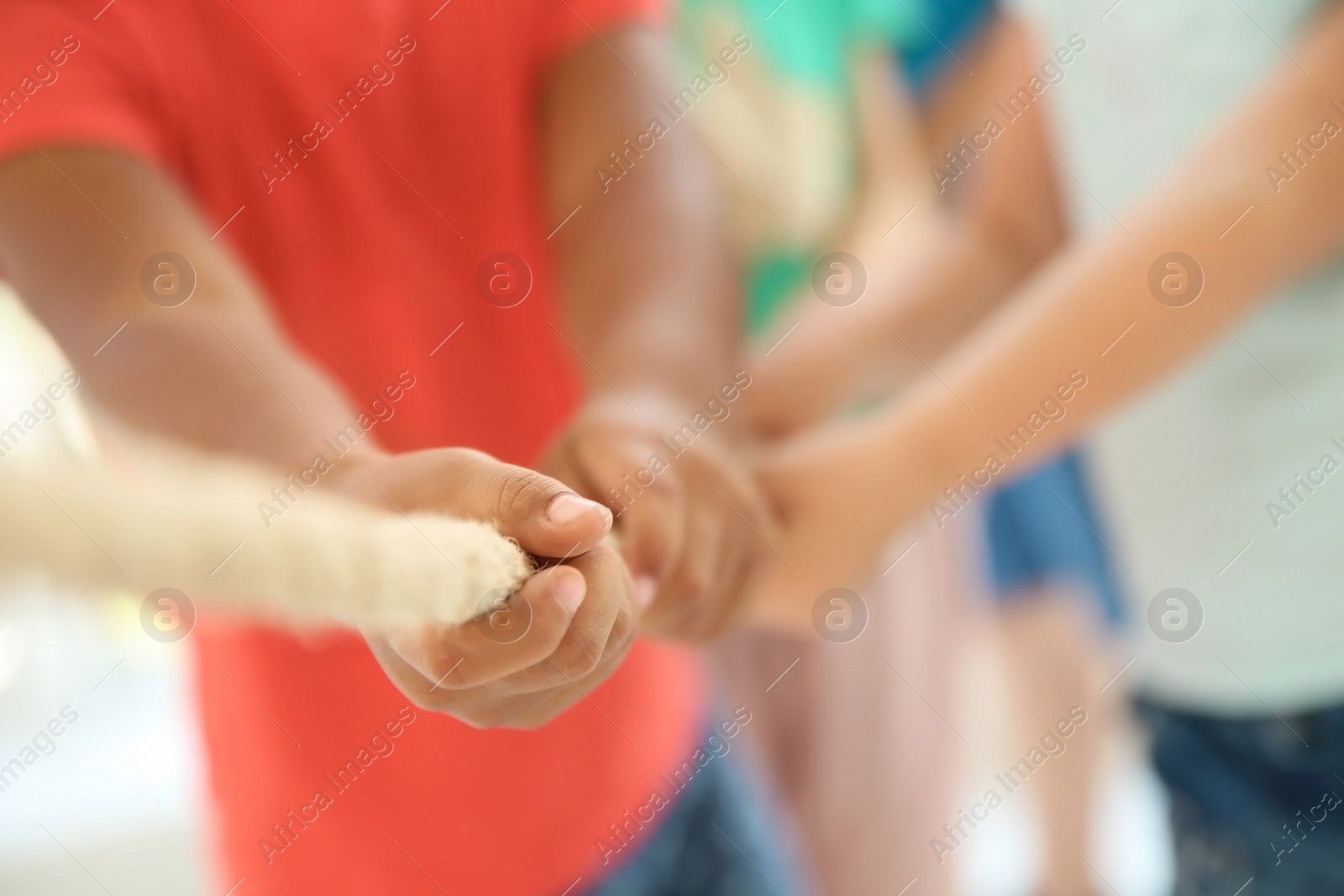 Photo of Little children pulling rope, focus on hands. Unity concept