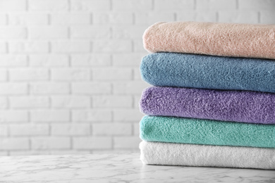 Photo of Stack of clean bath towels on white marble table. Space for text