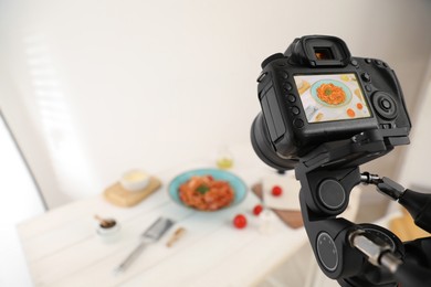 Photo of Professional camera with picture of spaghetti on display in studio, space for text. Food stylist