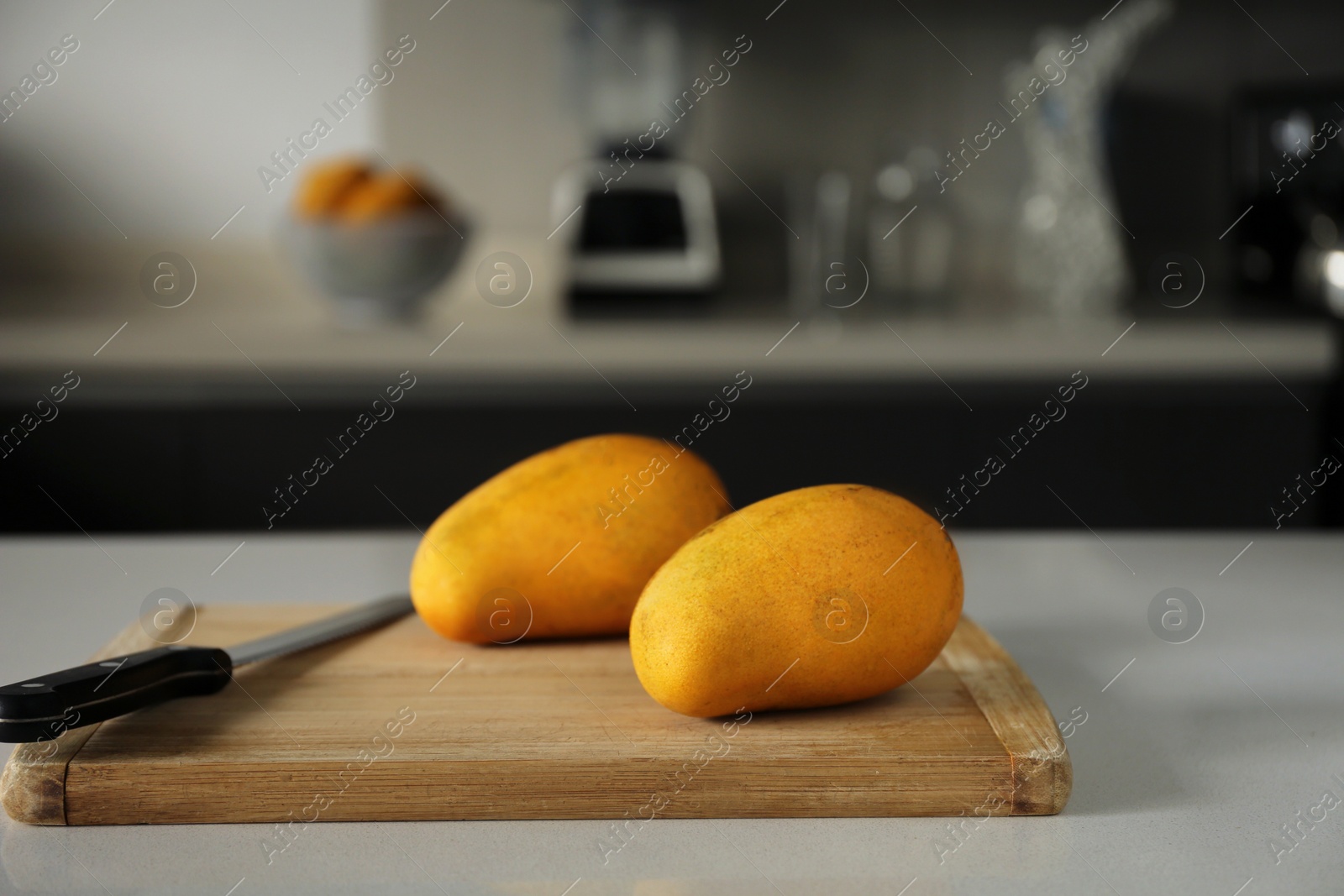 Photo of Delicious ripe mangos on white table in kitchen