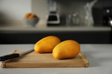 Photo of Delicious ripe mangos on white table in kitchen