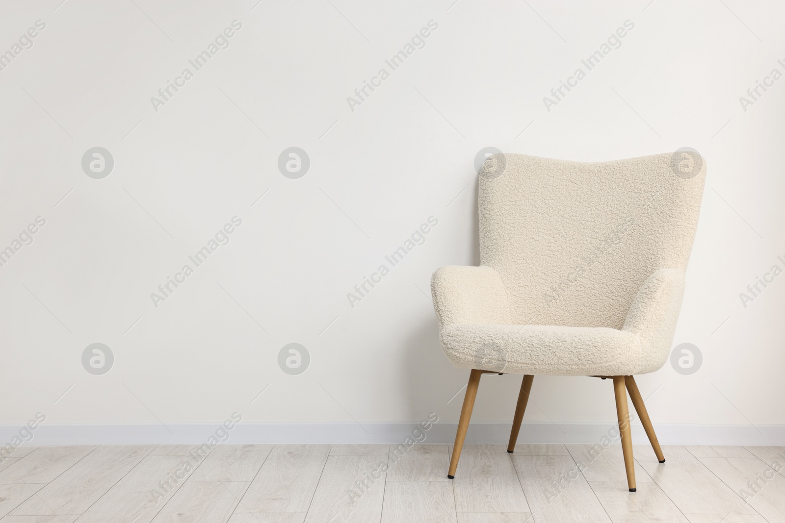 Photo of Comfortable armchair near white wall in room, space for text