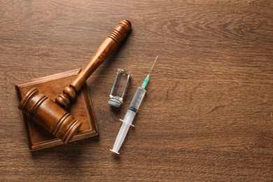Photo of Law concept. Gavel, syringe and vial on wooden table, top view. Space for text